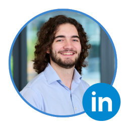 Gold-Vision CRM team member with long curly hair and beard wearing a light blue shirt, smiling in front of an office background, LinkedIn icon included.
